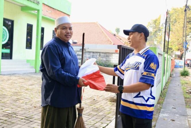 
 Kepala Dinas LH Kota Tangerang Yudi Pradana baikan Bendera kepada warga saat aksi bersih-bersih. Foto: Ist